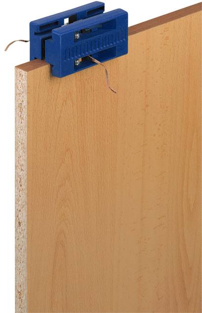 Un embout de perceuse à charnière bleu est fixé au bord supérieur d'une planche en bois. Deux fils dépassent de la perceuse.