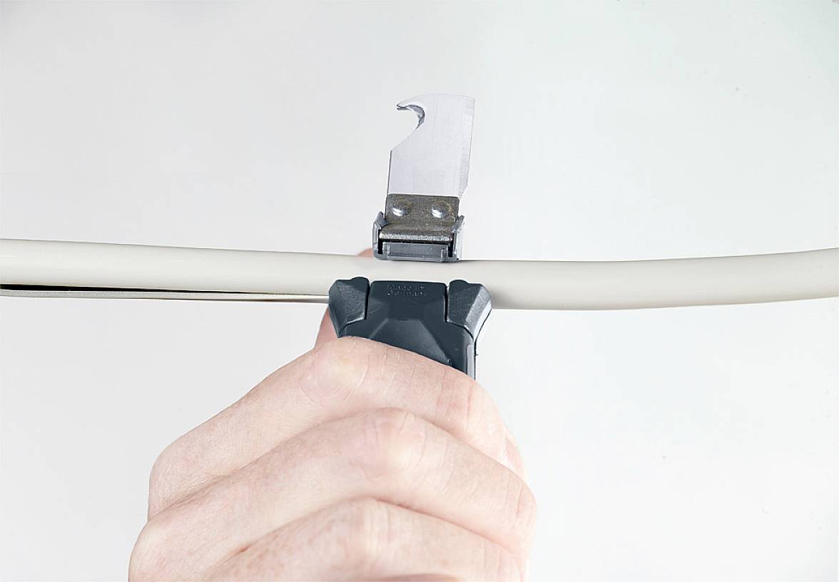 Une main tient un coupe-câble qui coupe un câble blanc. L'arrière-plan est clair et simple.