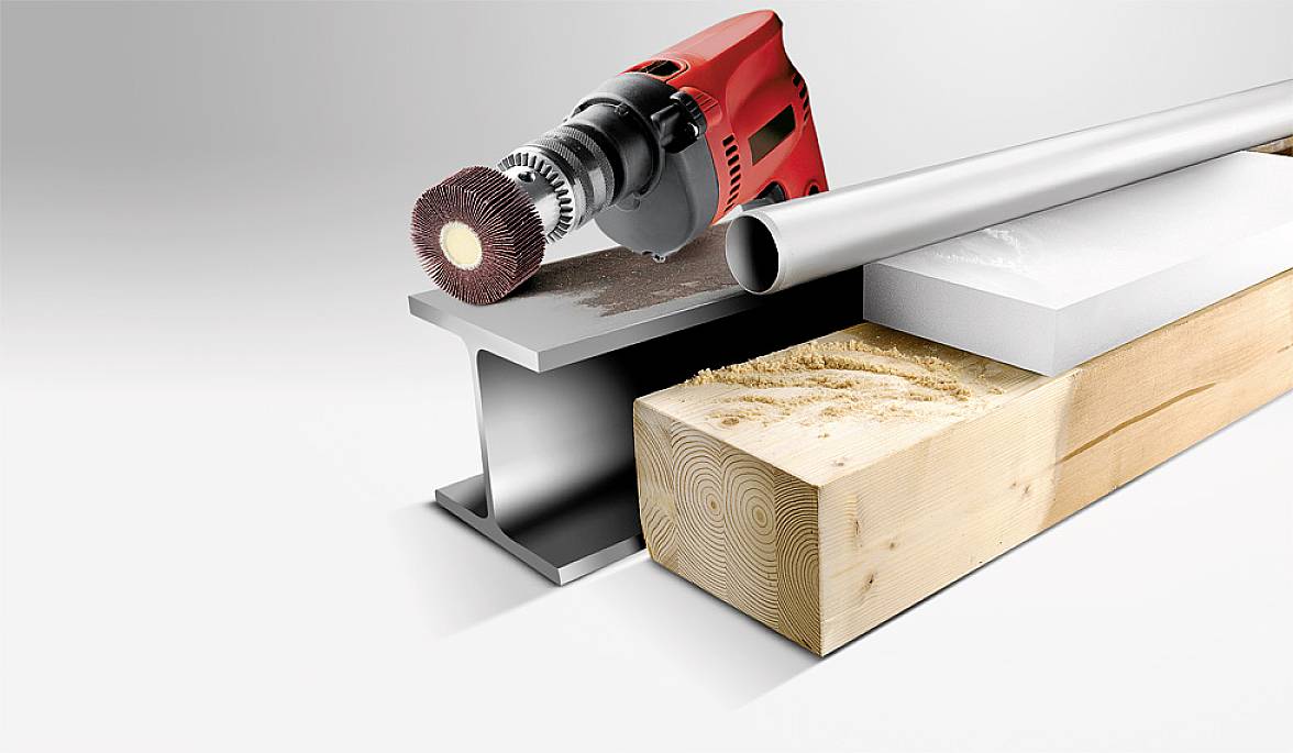 Une machine à poncer rouge et noire traite l'acier, le bois et le plastique, représentés par une plaque métallique, un bloc de bois et une plaque en plastique.
