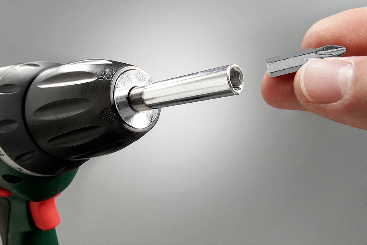 Visseuse avec porte-embout et embout amovible. Une main tient une embout de tournevis près de la visseuse.