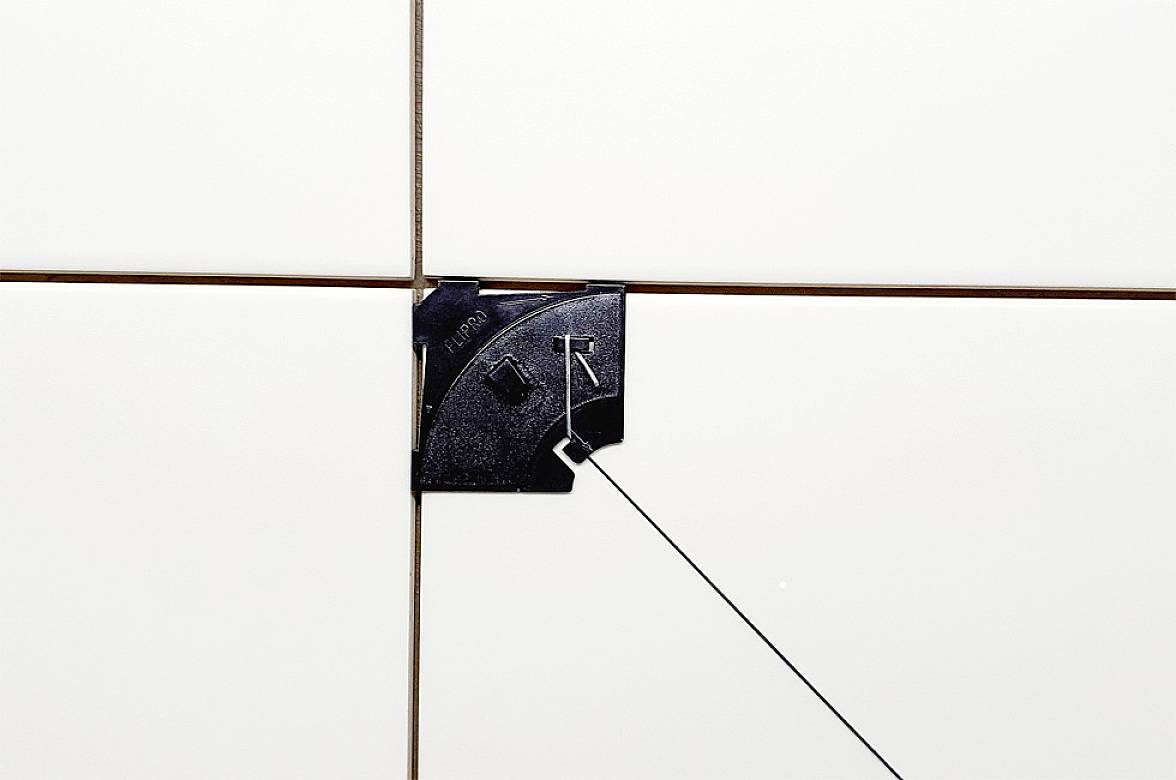 Croix d'espacement pour carrelage avec séparateur, permettant une largeur de joint uniforme pour des travaux de pose précis.