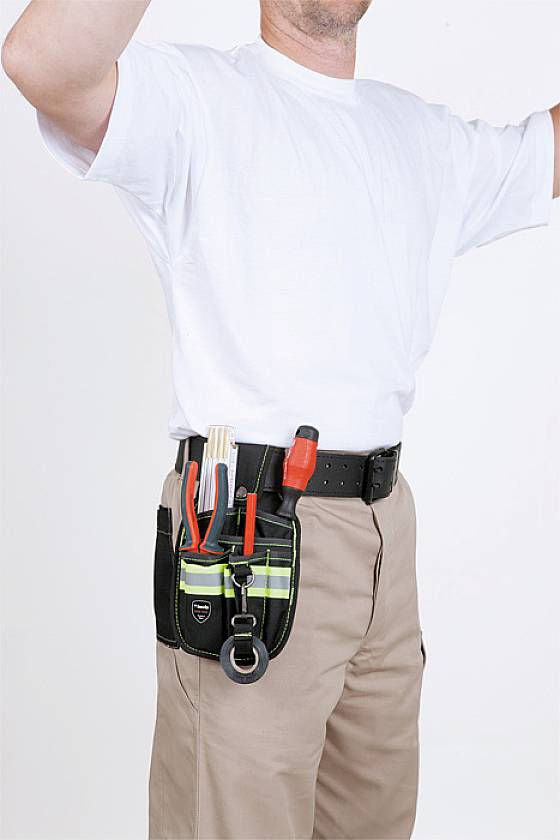 Homme portant un t-shirt blanc et un pantalon kaki, debout de profil. Il porte une ceinture à outils garnie de divers instruments.