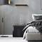 Chambre confortable avec des murs gris, lit moderne, table de chevet avec lampe et bouteille d'eau, lampadaire à gauche.