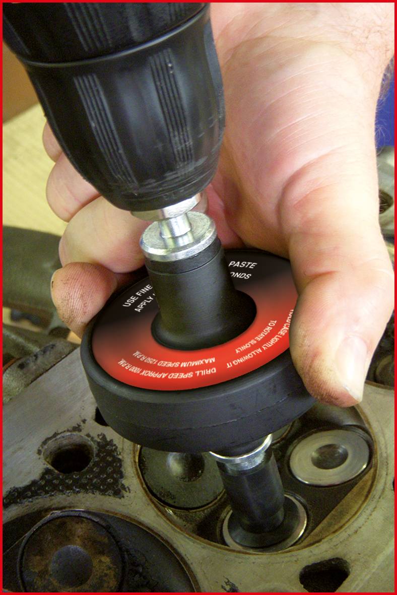 Gros plan d'une main utilisant un outil de rodage de siège de soupape dans la culasse d'une machine.
