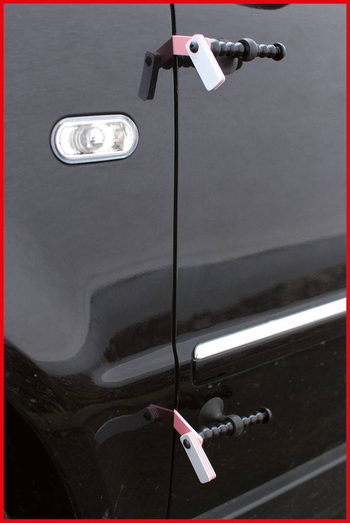 Une voiture avec deux poignées de porte qui ressemblent à des manivelles de fenêtre, montées sur une portière noire.