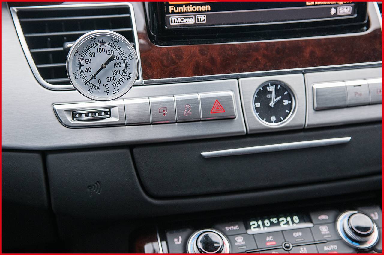 Intérieur d'une voiture avec tableau de bord. Un indicateur de température affiche environ 70 degrés. Éléments de commande visibles, y compris les feux de détresse.