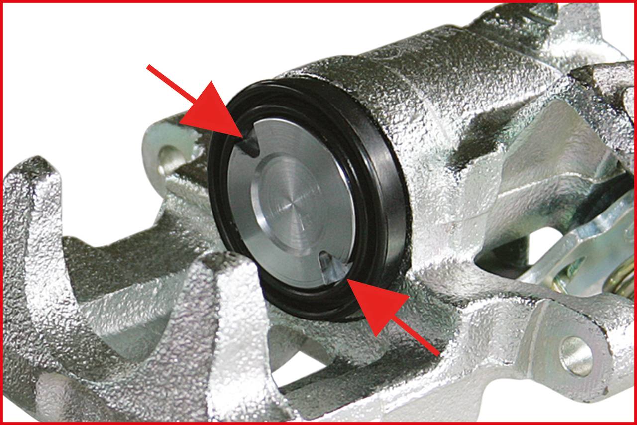 Gros plan d'un étrier de frein argenté avec des flèches pointant vers le piston de l'étrier. Composant principal d'un système de freinage automobile.