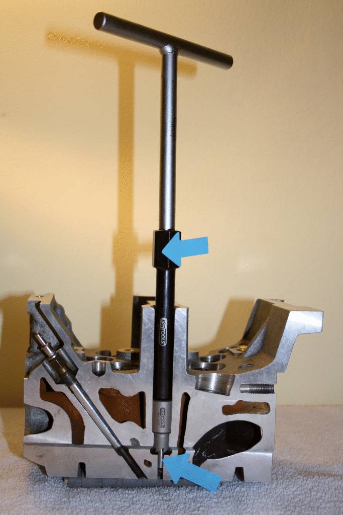 Un appareil de mesure T mesure le diamètre d'un trou dans un bloc métallique. Des flèches pointent vers l'instrument de mesure et le point de mesure.