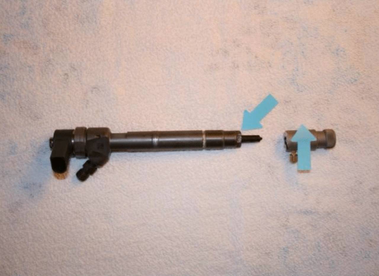 Une longue tige métallique cylindrique avec deux flèches pointant vers un raccord métallique séparé et plus court sur la droite.