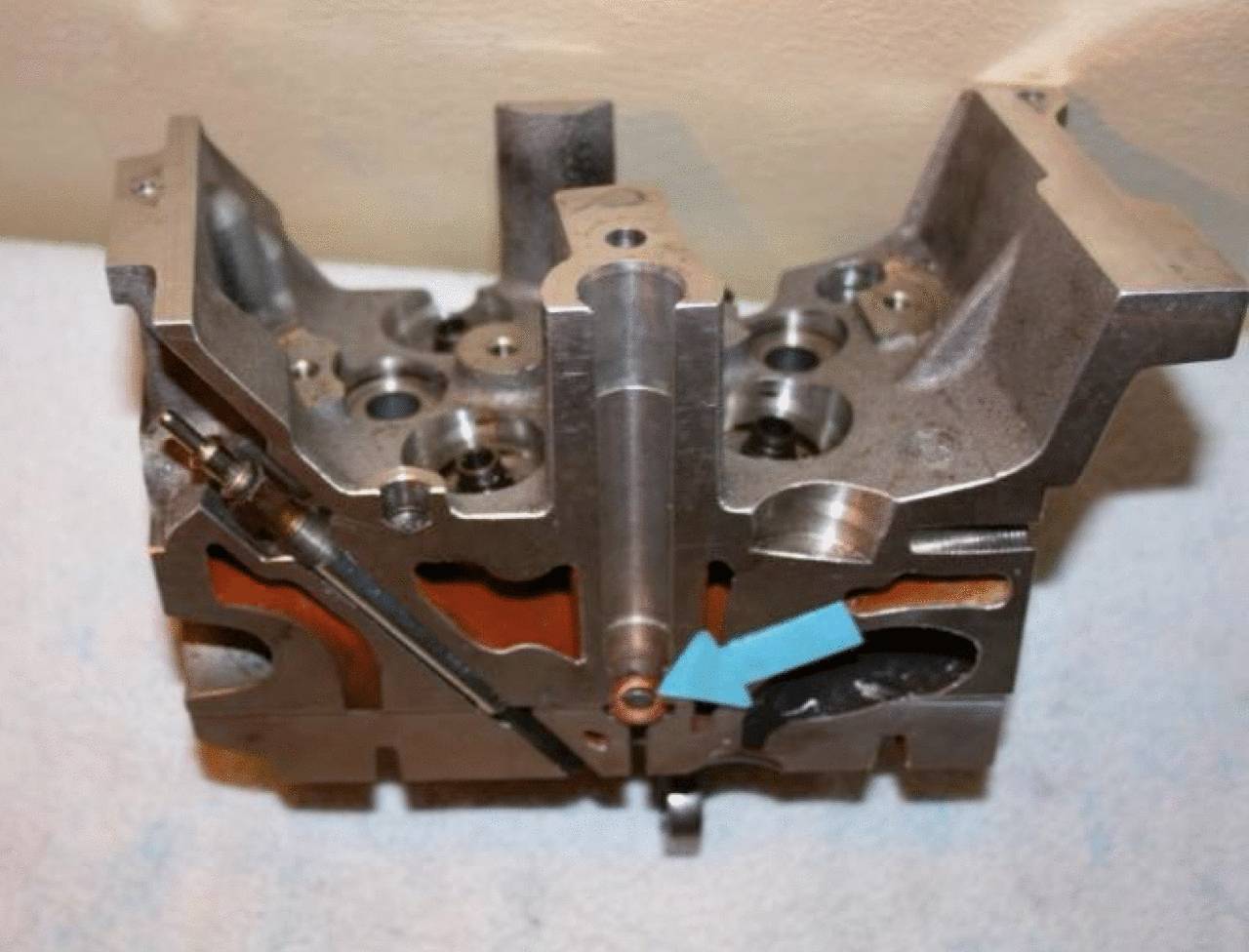 Un bloc-moteur avec un marquage de flèche bleue indiquant une pièce spécifique à l'intérieur.