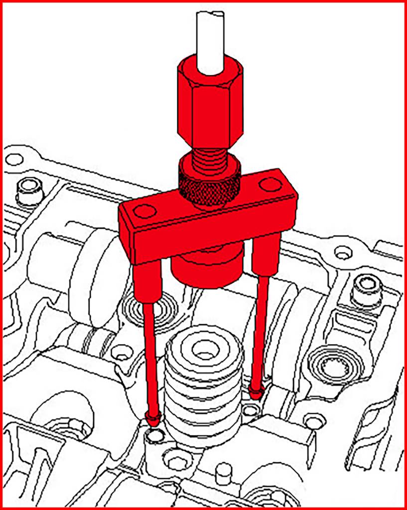 Un extracteur rouge est installé sur une culasse de moteur pour retirer un porte-soupape.