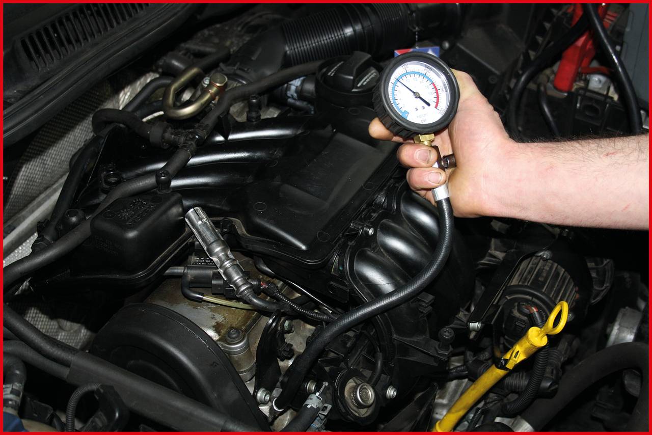 Une main tient un appareil de mesure contre le moteur d'une voiture pour vérifier la pression des pneus. L'appareil indique une pression d'environ 150 psi.