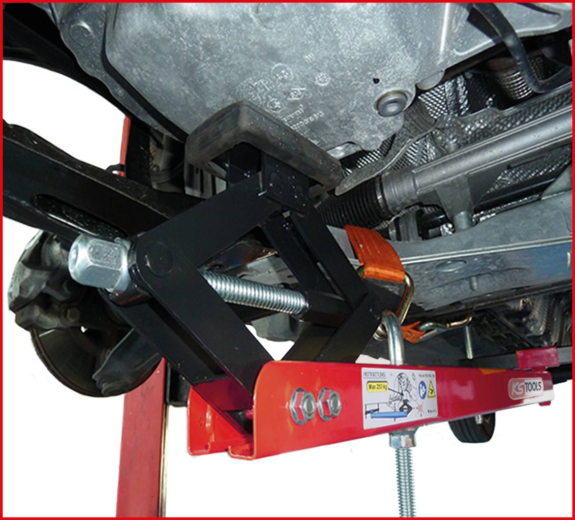 Un lève-moteur supporte un moteur de voiture dans un environnement d'atelier automobile. Un cadre métallique rouge et des mécanismes à vis sont visibles.