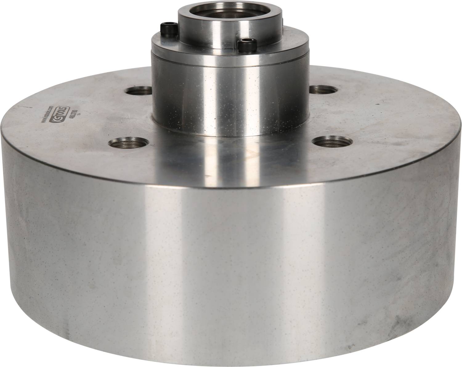 Bloc métallique argenté, rond, avec un embout cylindrique central et quatre perçages visibles. Utilisé dans des applications mécaniques.