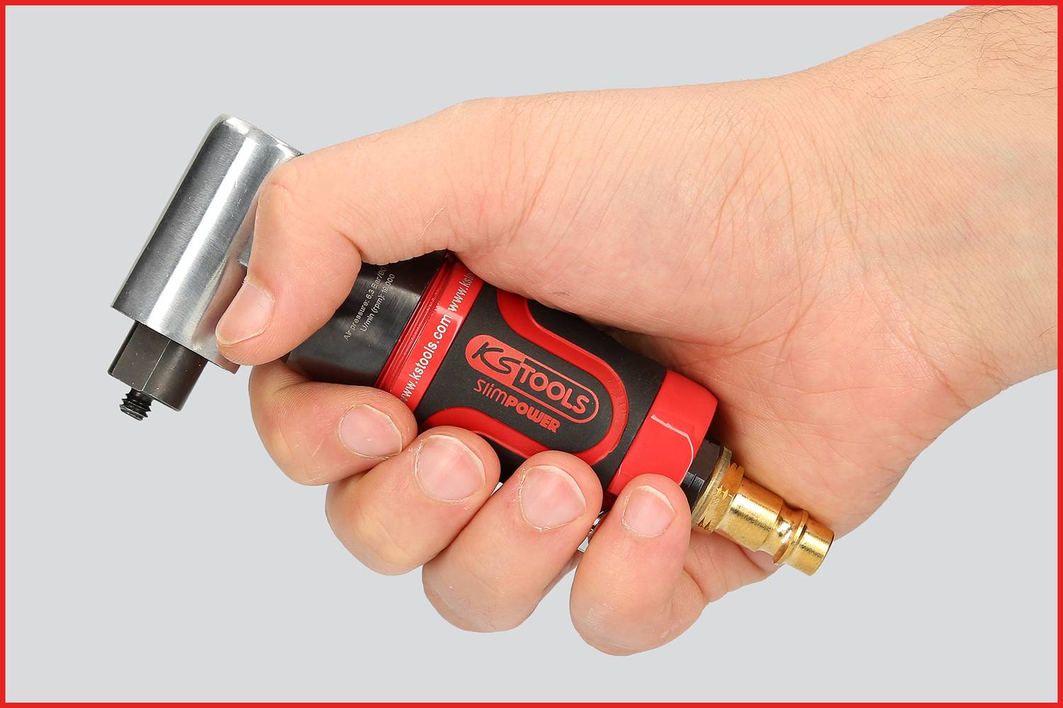 Une main tient un outil modifié rouge avec un design noir et une pointe dorée, probablement un dispositif à air comprimé.