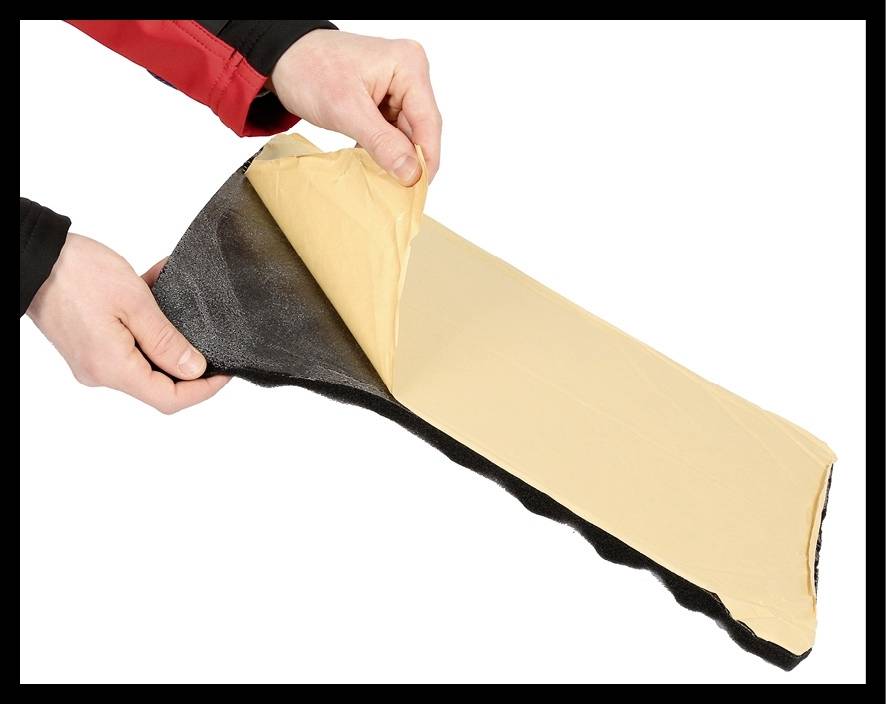 Deux mains retirent un film de protection d'une coupe transversale d'un matériau isolant, révélant ainsi sa surface adhésive.