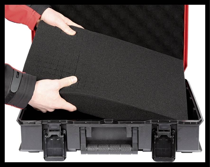 Une valise noire s'ouvre. Des mains soulèvent un bloc de mousse noir de l'intérieur de la valise.