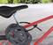 Un casque de vélo noir est solidement fixé au cadre d'un vélo rouge. En arrière-plan, on aperçoit un chemin pavé.