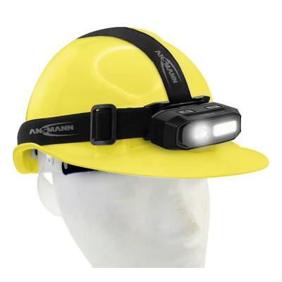 Un casque de sécurité jaune avec une lampe frontale noire montée dessus. La lampe est allumée et pointe vers l'avant.
