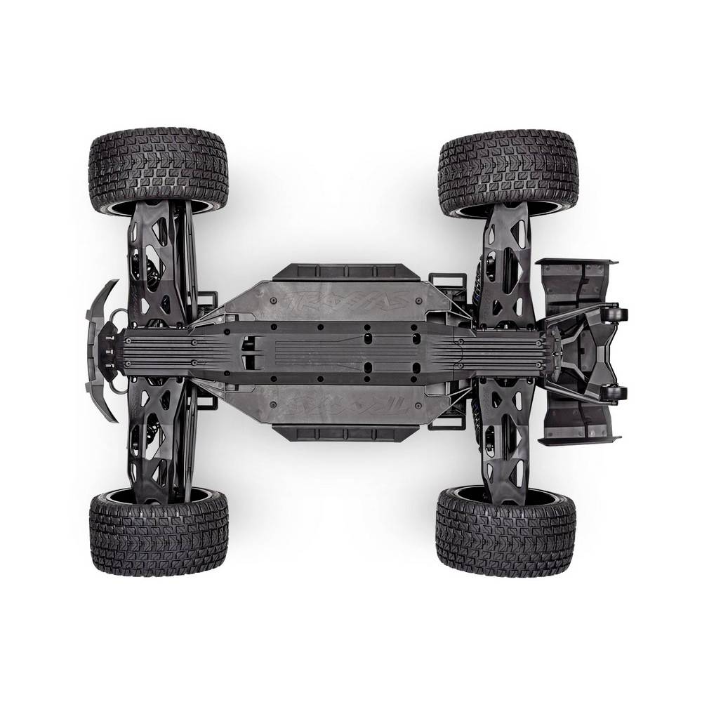 Le dessous d'un véhicule tout-terrain télécommandé avec de grands pneus à profil et une suspension et une structure de châssis détaillées et visibles.