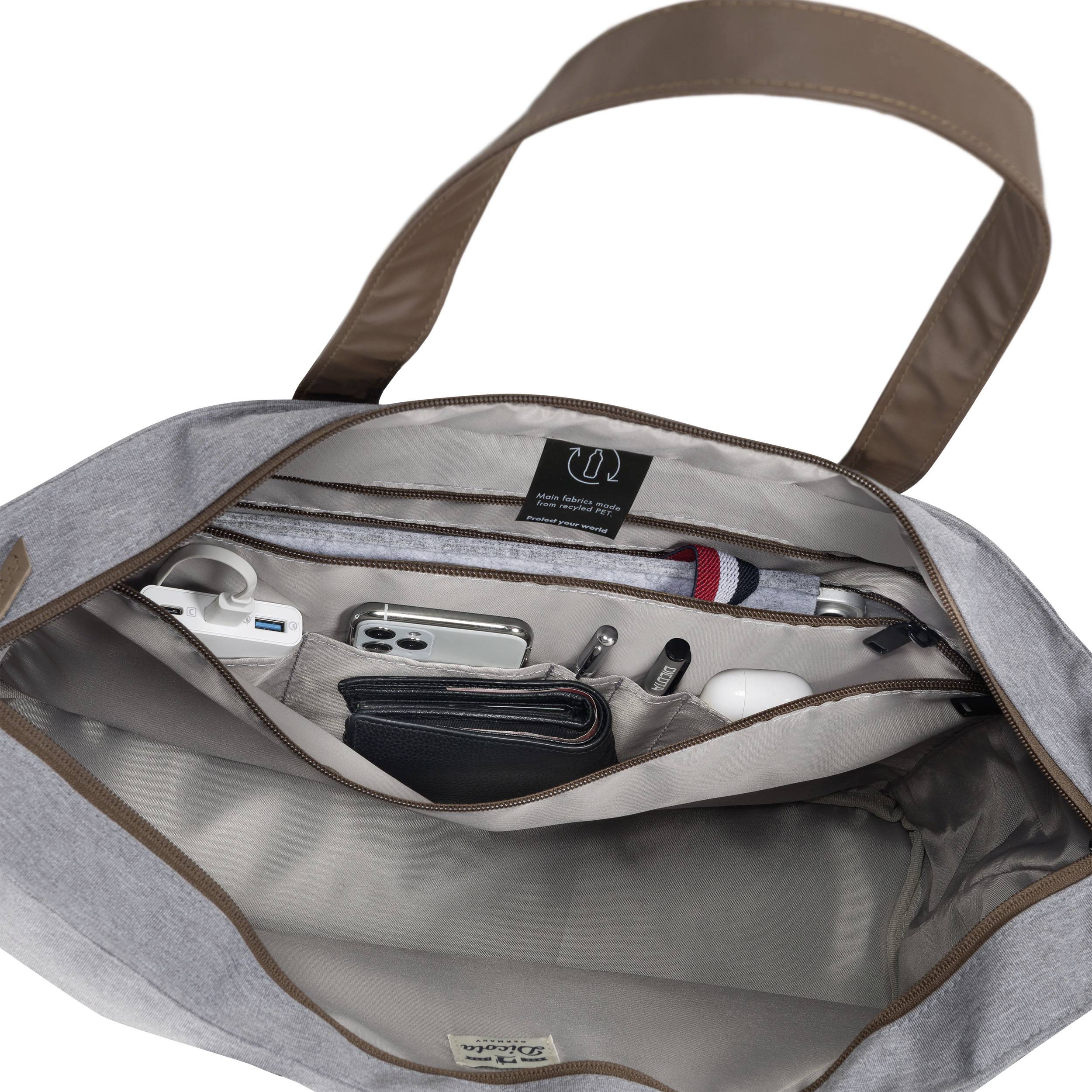 Un sac à main gris ouvert révèle des compartiments intérieurs bien organisés contenant un smartphone, des écouteurs, des stylos et un portefeuille.