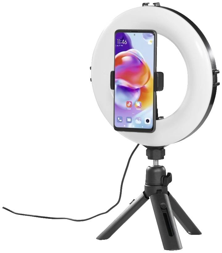 Un smartphone est monté dans un anneau lumineux rond sur un petit trépied. L'anneau lumineux est branché et éclairé.