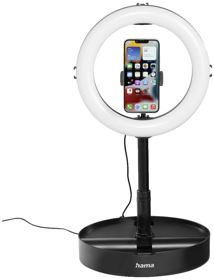 Un smartphone est fixé dans le support d'un trépied de lampe annulaire. La lampe annulaire est branchée à une prise de courant.