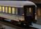 Un train miniature avec des wagons éclairés sur un rail. Le wagon est à l'échelle HO, bleu et blanc, et porte l'inscription '2' sur le côté.