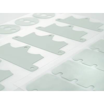 Des formes rectangulaires grises en plastique avec des éléments percés sont disposées de manière symétrique sur un fond blanc.