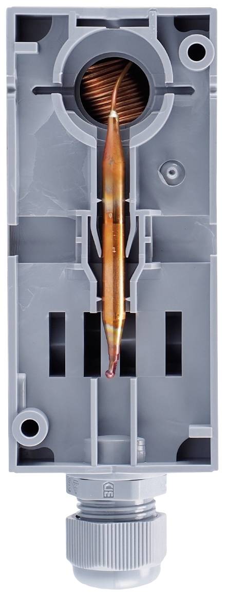 Un boîtier en plastique gris avec un ressort de tube en cuivre à pression verticale, utilisé pour mesurer le débit ou la pression.