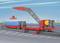 Une grue rouge soulève un conteneur sur un train de marchandises dans le port. Une ville et la mer sont visibles en arrière-plan.