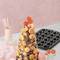 Une tour pyramidale de mini-cupcakes avec des accents décoratifs rouges et orangés, posée sur une table avec des accessoires de pâtisserie.