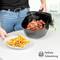 Une personne dépose des ailes de poulet frites fumantes d'une friteuse sur une assiette de frites, symbolisant une cuisson sans graisse.
