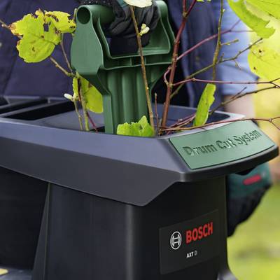 Gros plan sur une station d'outils de jardin noir avec l'inscription 'Drum Cut System' et le logo Bosch. Un outil de jardin vert avec des plantes dessus.