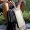 Une personne est assise dehors sur une chaise de camping, tenant un thermos et portant un sac à dos gris avec un panneau solaire à l'avant.
