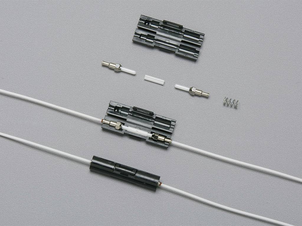Connexion de câble coaxial : Deux sections d'un câble coaxial sont connectées par un connecteur. Les composants individuels du connecteur sont visibles en haut.