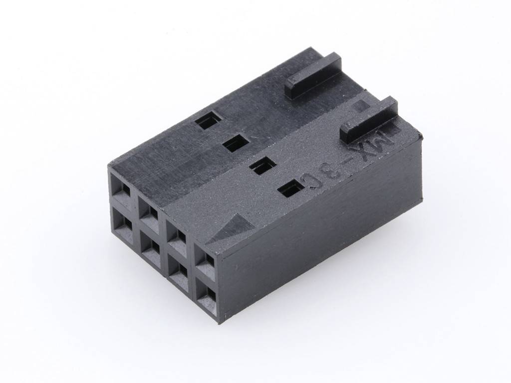 Un connecteur en plastique noir rectangulaire avec plusieurs ouvertures carrées, repose sur une surface blanche.