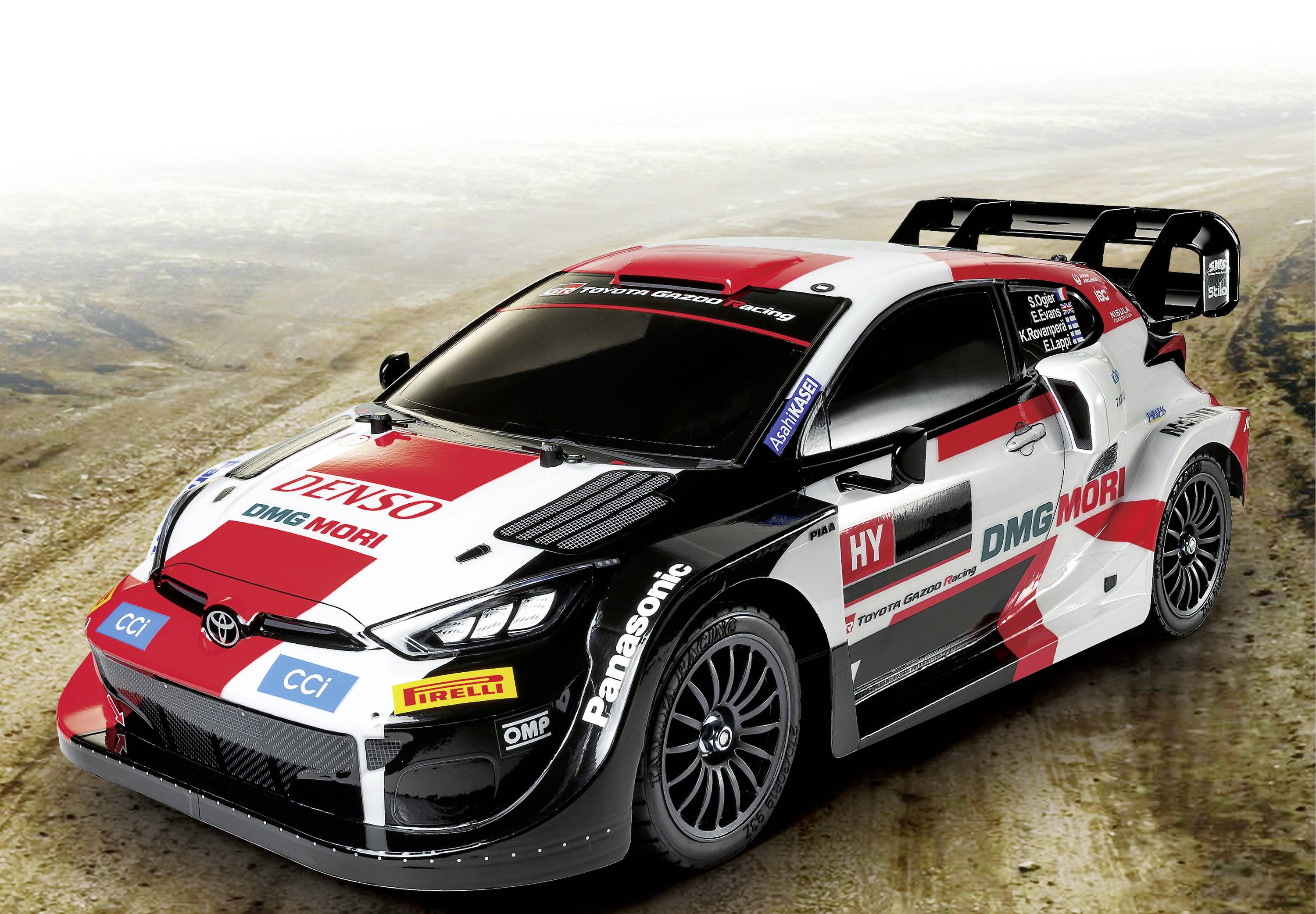 Une voiture de rallye aux couleurs vives et aux logos de sponsors est garée sur une surface poussiéreuse. Elle a l'air rapide et sportive.