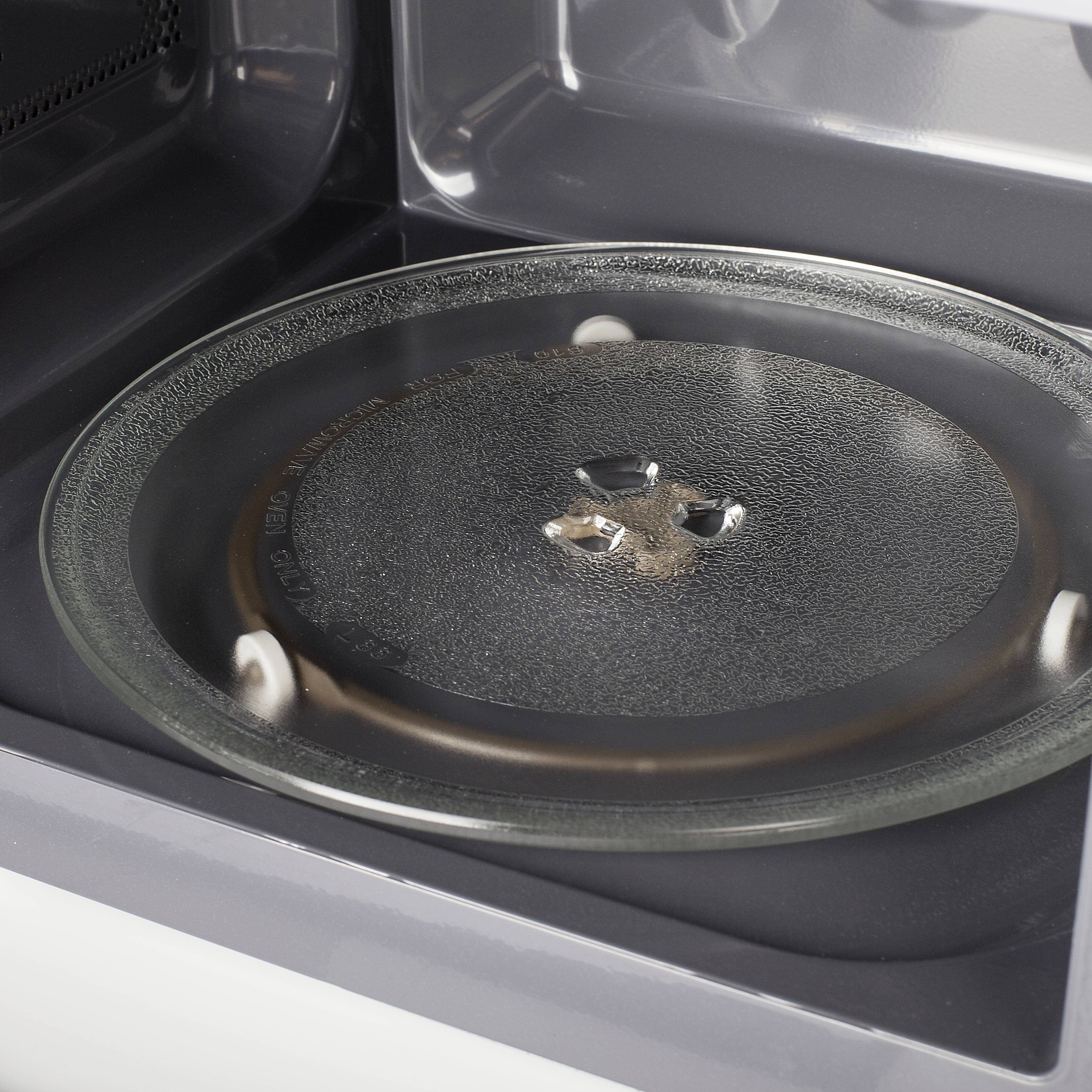 Un plateau en verre pour micro-ondes avec trois petites roues à l'intérieur gris d'un four à micro-ondes.