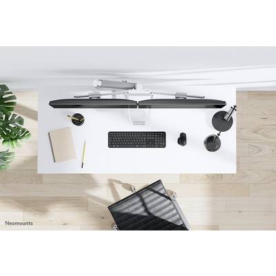 Bureau vu de dessus avec clavier, support de moniteur, carnet de notes, stylo, souris et lampe. Environnement de bureau moderne.
