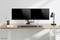 Un bureau bien rangé avec deux écrans, un clavier, des accessoires de bureau et une lampe. Design minimaliste et moderne.