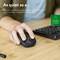 Une main tient une souris d'ordinateur silencieuse sur une table à côté d'un clavier. Texte : « Aussi silencieuse que... »
