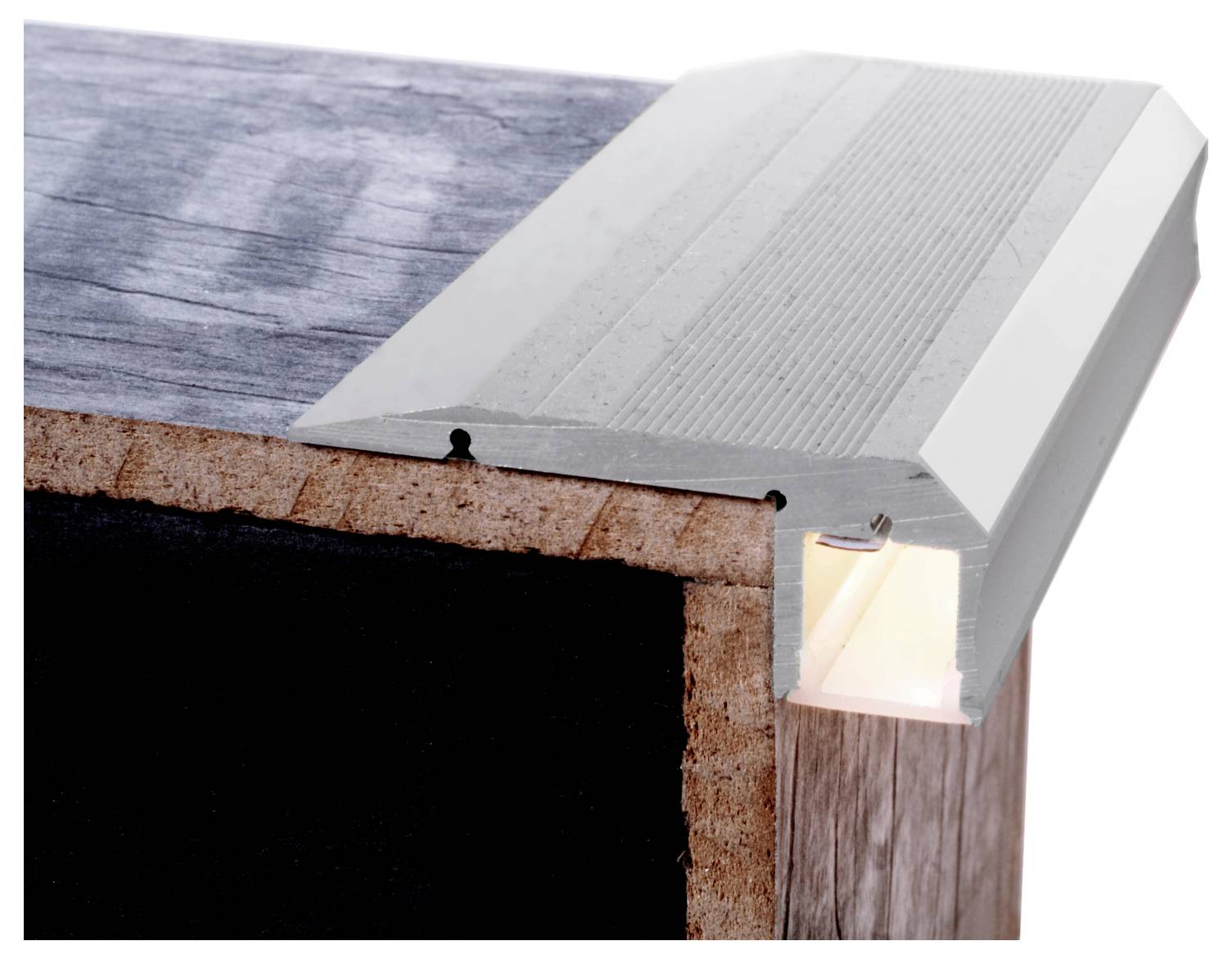 Gros plan d'un profilé LED en aluminium argenté fixé sur le bord d'une surface, avec un diffuseur éclairé laissant voir une lumière chaude à l'intérieur.