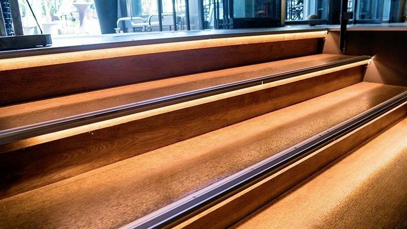 Marches d'escalier éclairées dans un bâtiment moderne, indiquant le chemin vers un étage supérieur.