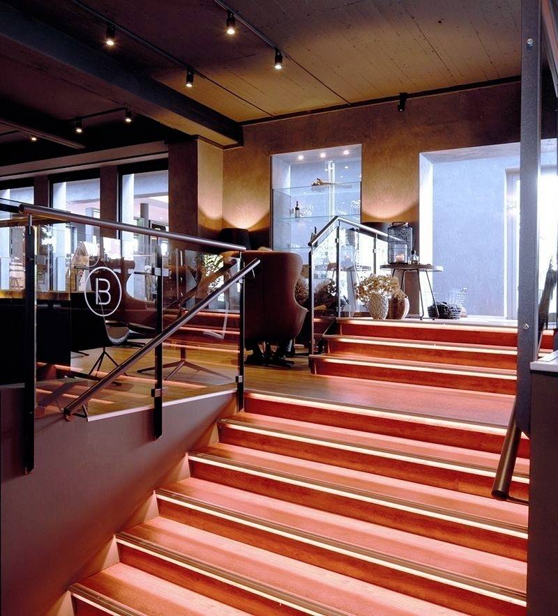 Un escalier moderne aux marches rouges dans un intérieur élégant, entouré de vitrines en verre et d'éléments décoratifs.