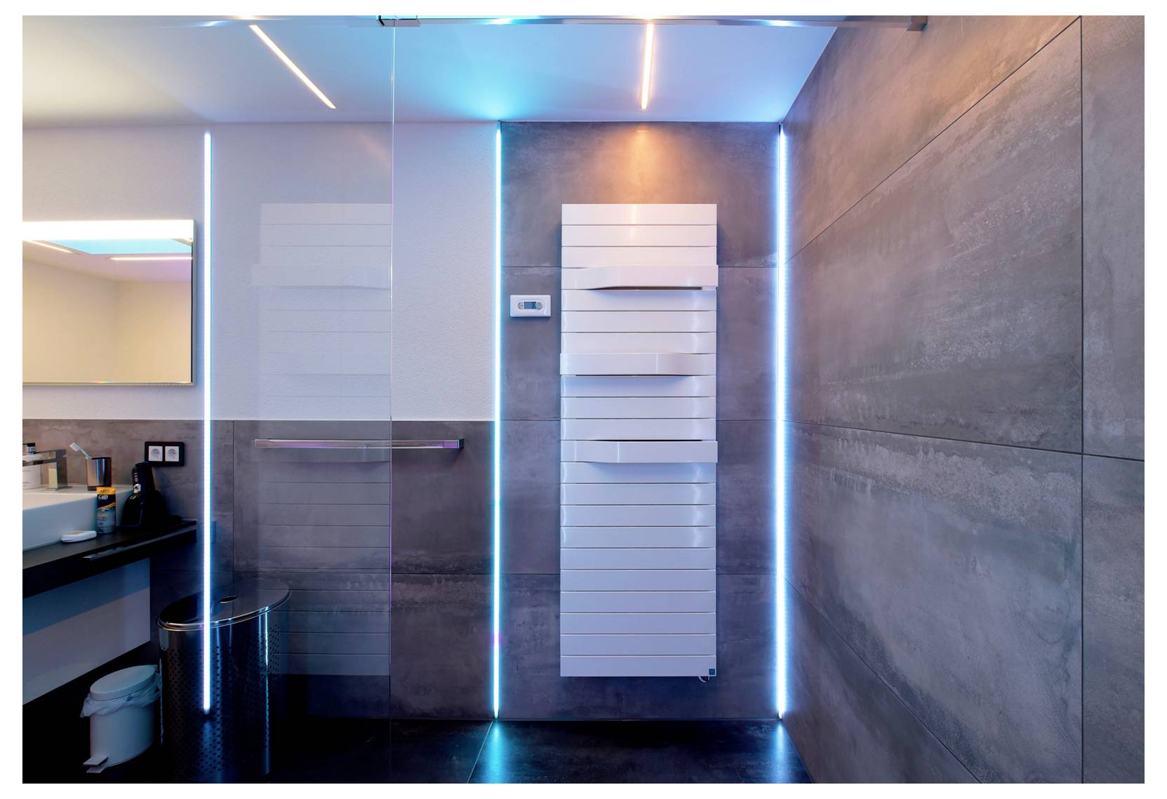 Salle de bain moderne avec cabine de douche en verre, sèche-serviettes blanc et éclairage LED bleu d'ambiance sur des murs carrelés gris.