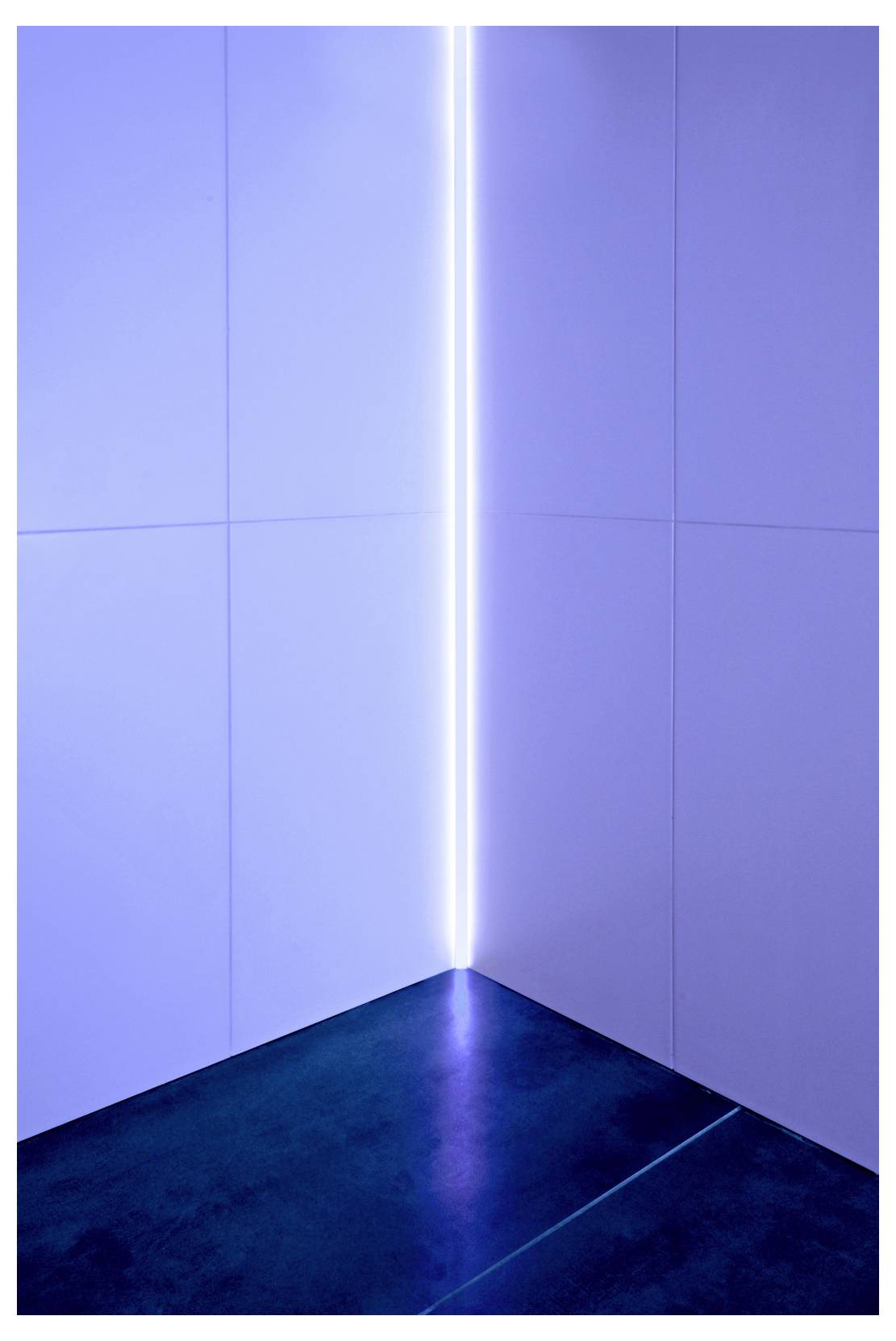 Coin minimaliste éclairé en bleu, avec une bande lumineuse verticale et un sol sombre, créant une installation d'intérieur futuriste.
