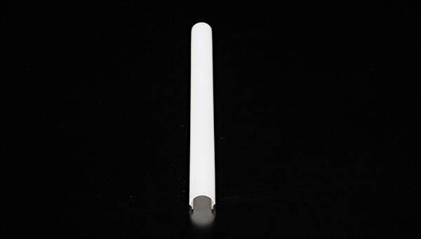Une tube en plastique blanc et vertical est posé sur une surface noire.