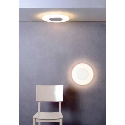 Une chaise blanche est placée devant un mur avec deux lampes circulaires lumineuses dans une pièce moderne.