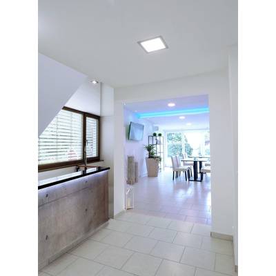 Entrée moderne avec des carreaux clairs, un comptoir en bois à gauche et vue sur une salle à manger éclairée avec une porte vitrée en arrière-plan.
